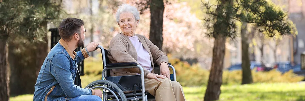 Pflegerin im Gespräch mit einer Seniorin im Park